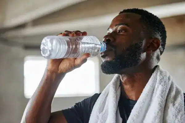 Image of man drinking water to improve hydration Bracknell 	 after work out.
